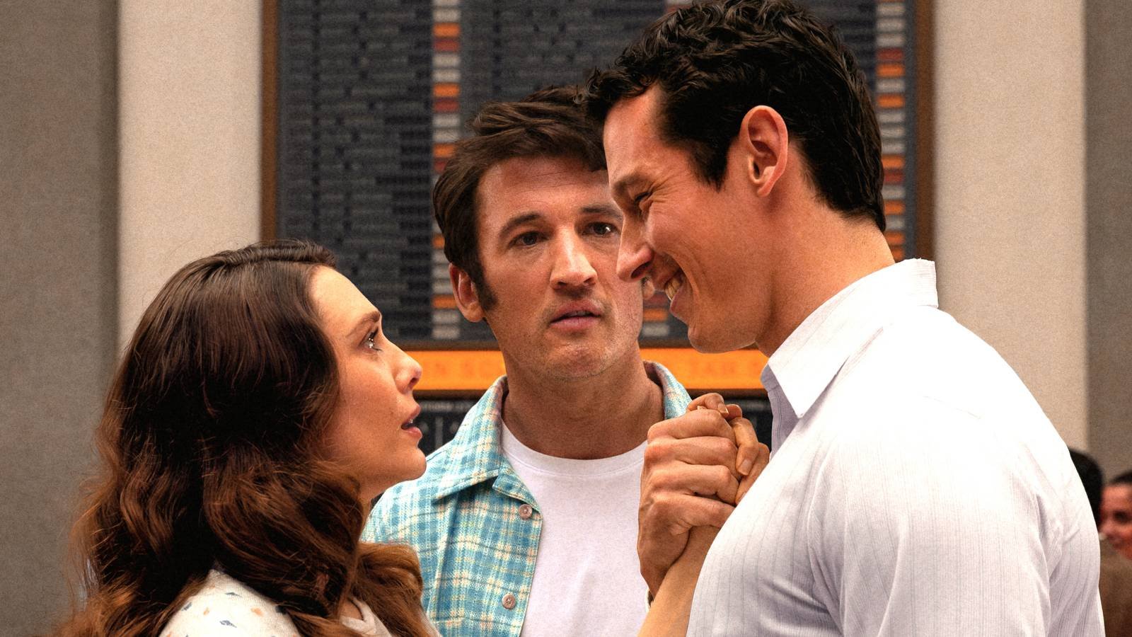 Miles Teller looking on as Callum Turner holds Elizabeth Olsen's hand to his chest in Eternity 2025