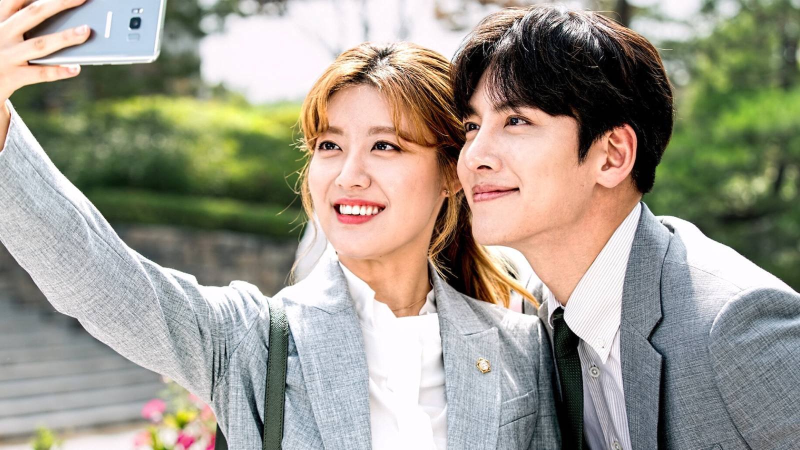 A man and woman take a selfie in Suspicious Partners.