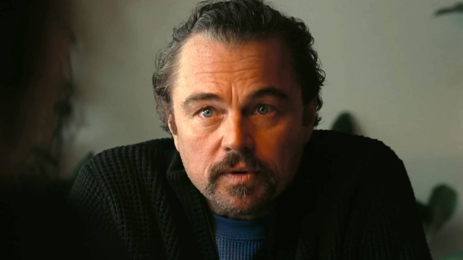 Leonardo DiCaprio's Bob looking seriously while talking to someone in One Battle After Another