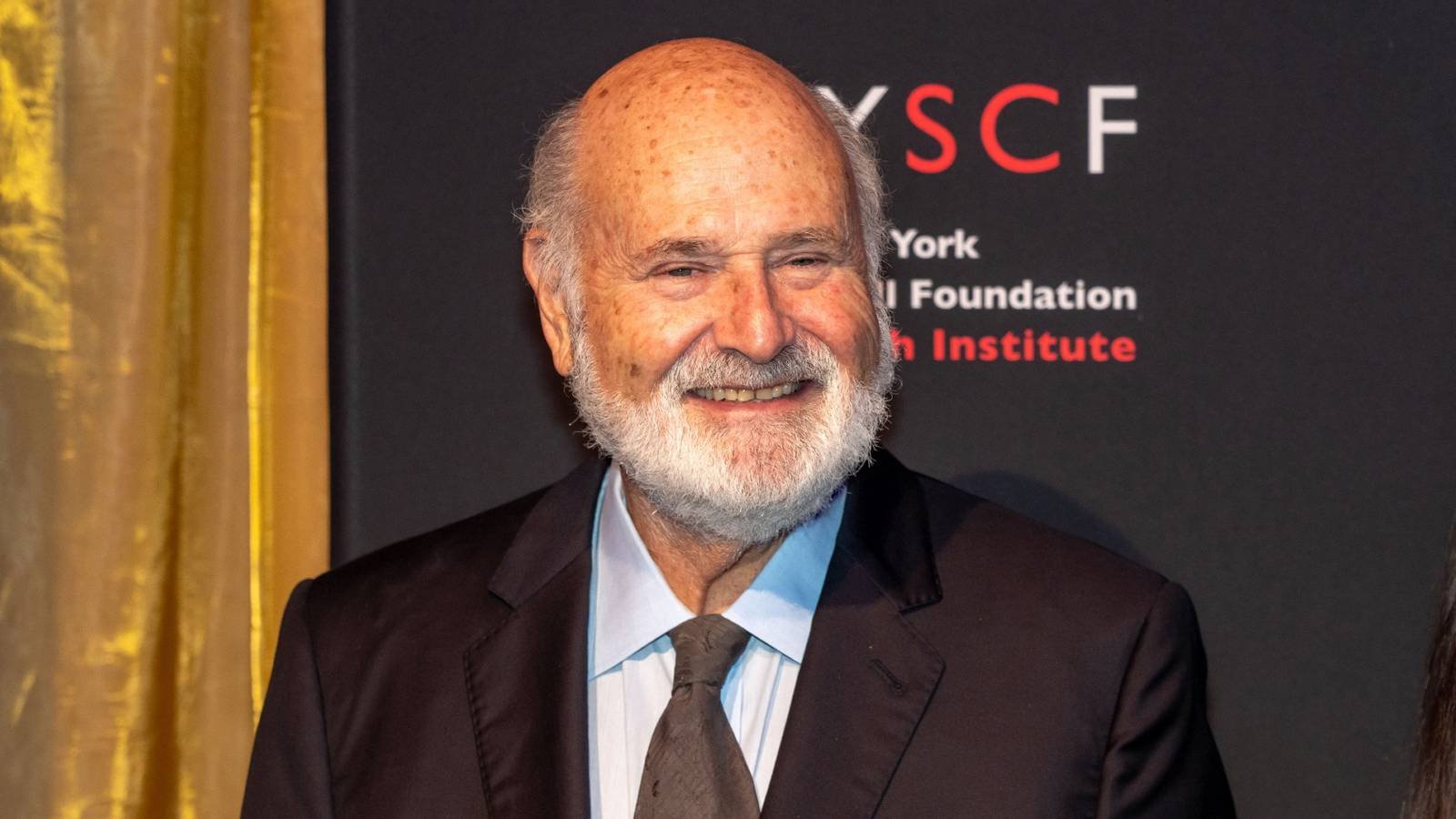 Rob Reiner smiles while standing on the red carpet