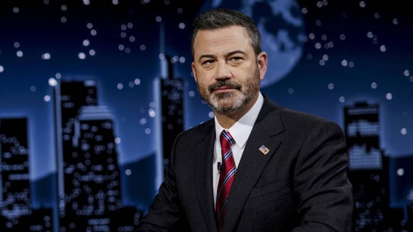 Jimmy Kimmel sitting at his desk with a serious look on his face